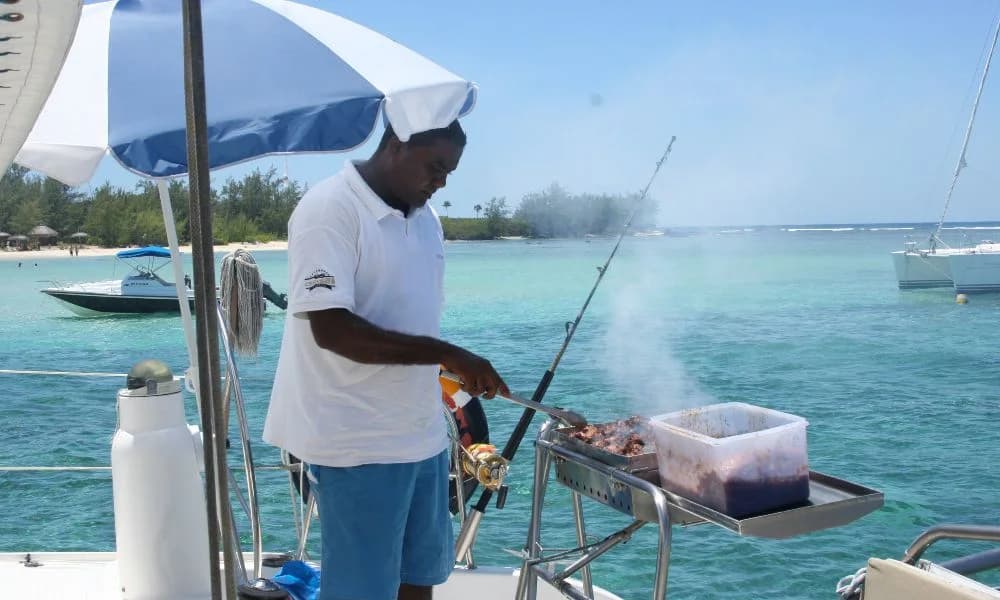 Crew member preparing a barbecue lunch aboard a catamaran
