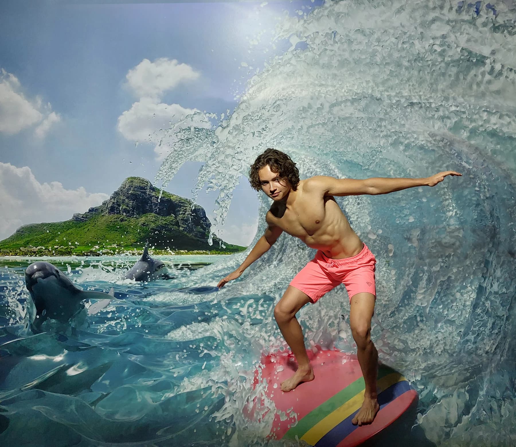 A visitor poses on the surfing illusion with a painted Mauritius backdrop