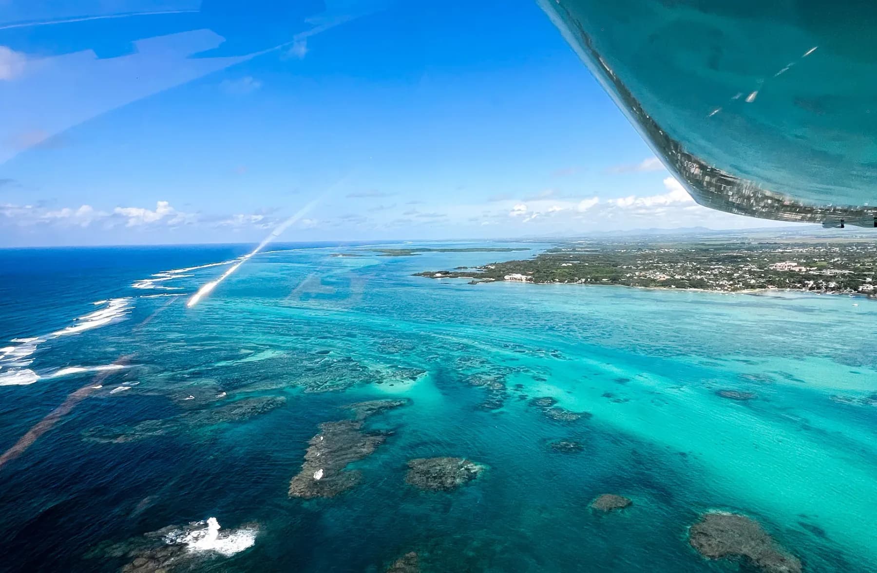The wing and float of a seaplane over the reef and the coast of Mauritius