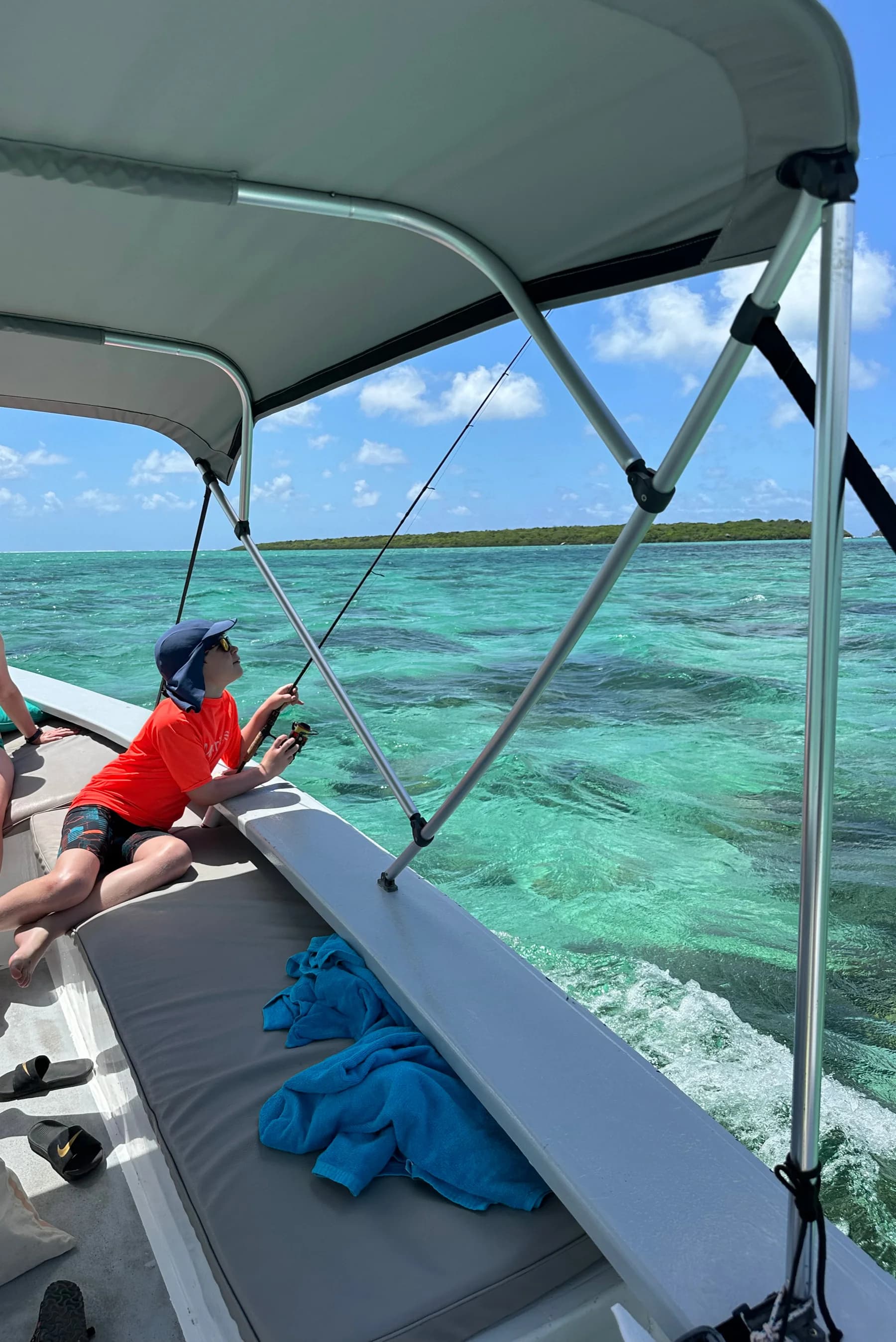 A guest under the boat's sunshade on the lagoon
