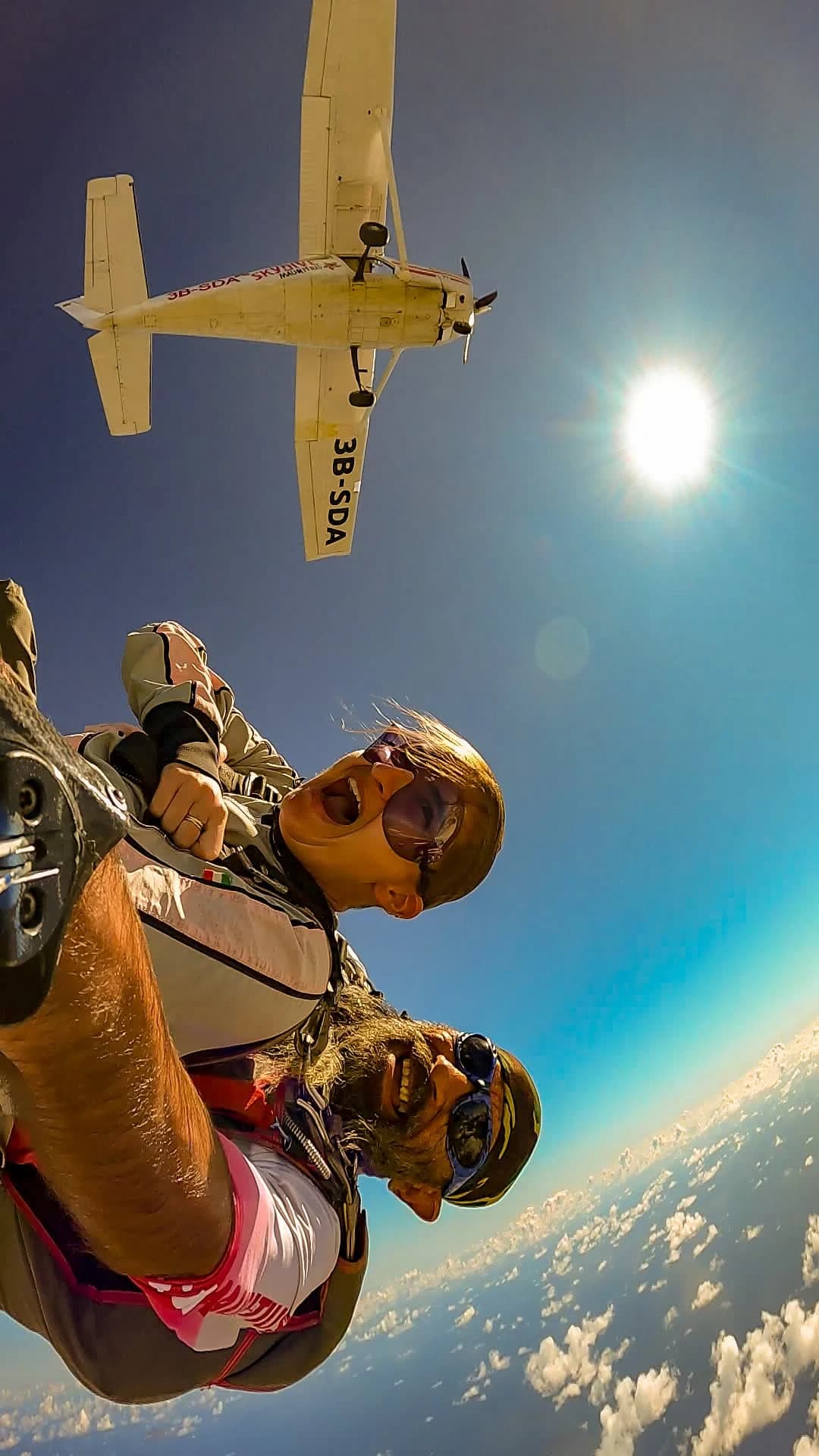 Hochformatfoto eines Tandemabsprungs mit dem Flugzeug darüber