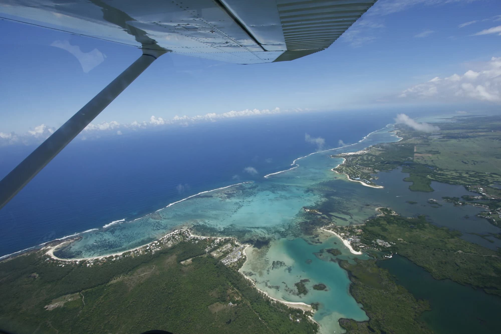 Blick unter der Tragfläche des Flugzeugs hindurch auf die Lagune und die Küste
