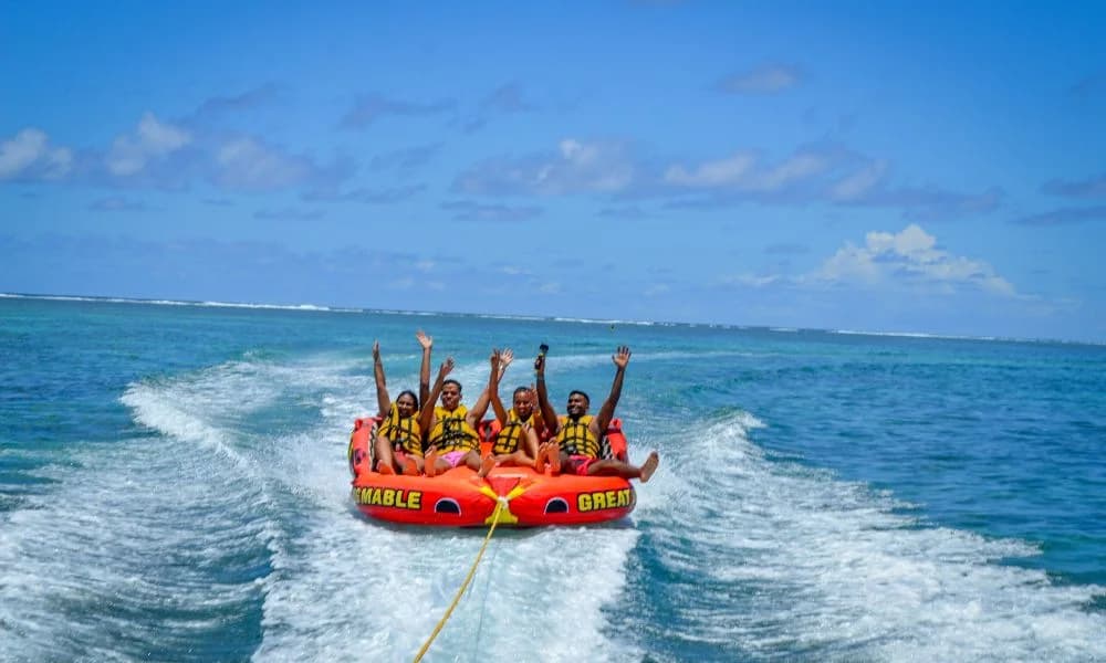 Four guests riding an inflatable tube behind a boat in Belle Mare Lagoon