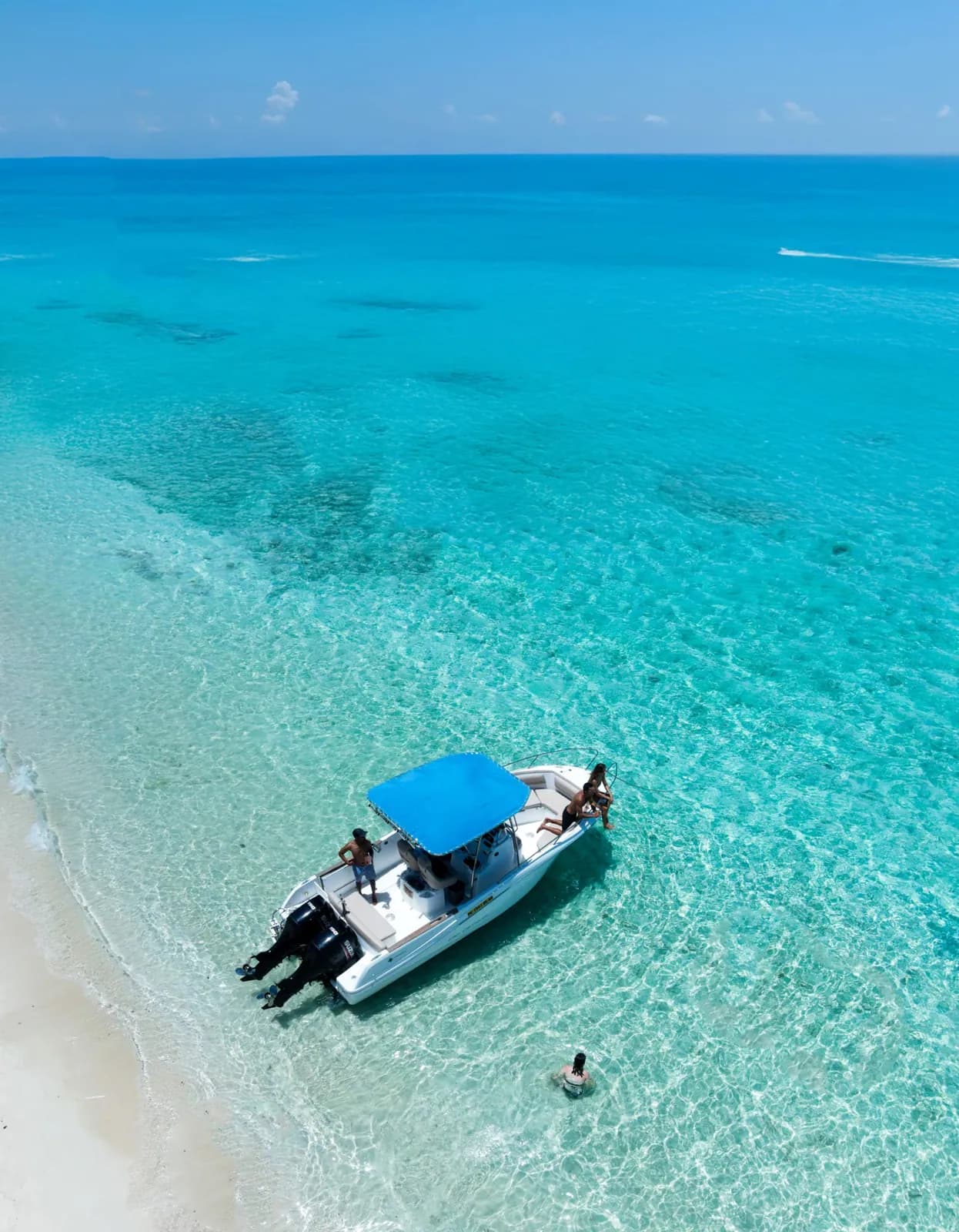 Un bateau à moteur ombragé près d’une plage de sable blanc