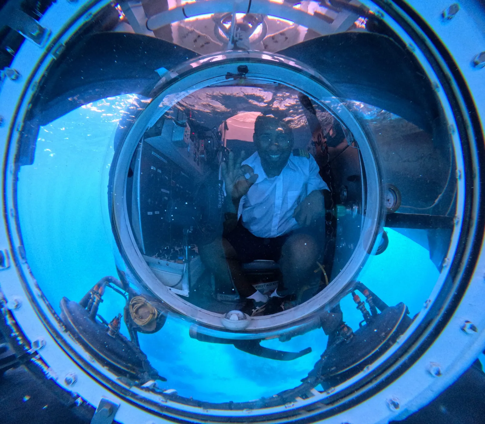 Des passagers vus à travers le hublot circulaire d’un sous-marin