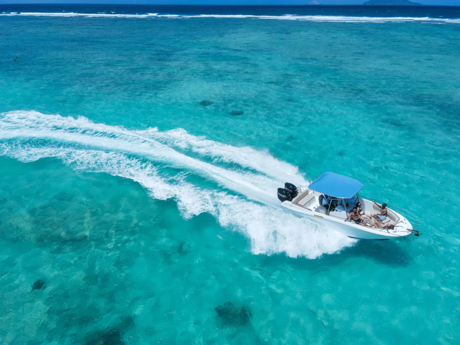 A speedboat travelling across a bright turquoise lagoon