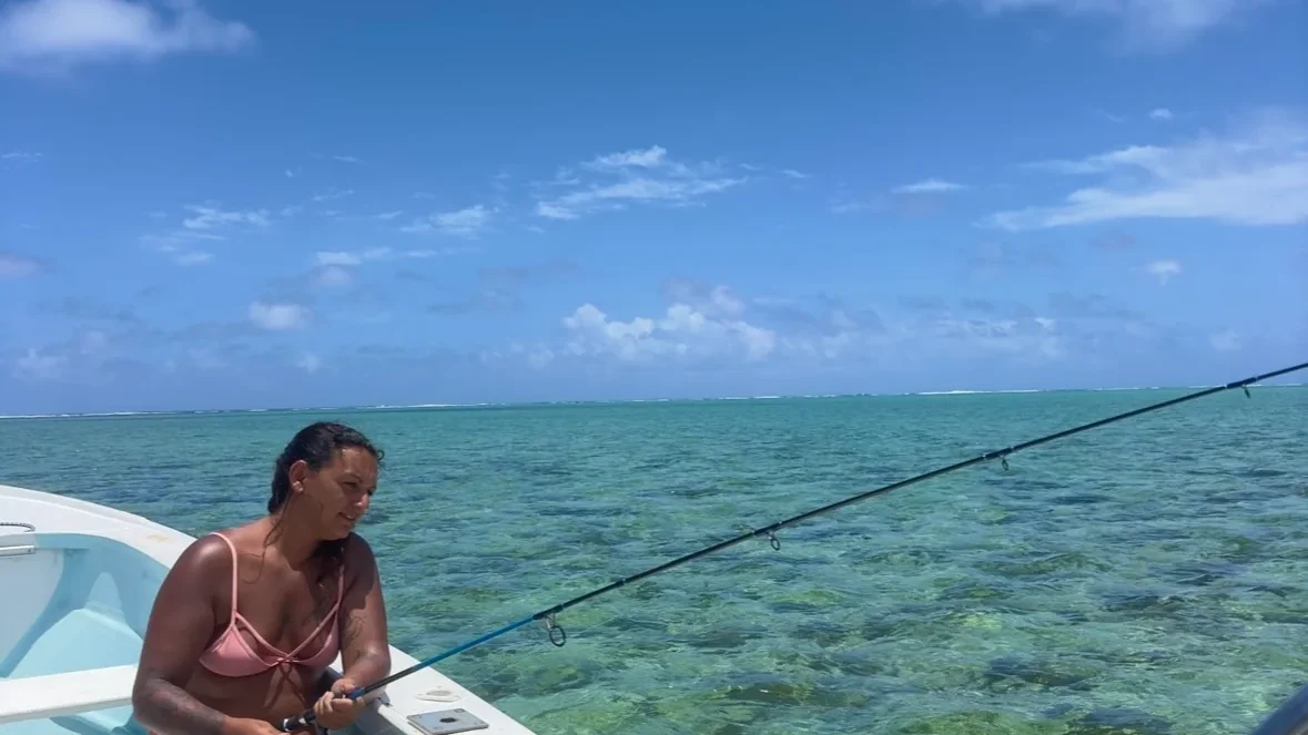 An angler casting from a boat in the shallow lagoon