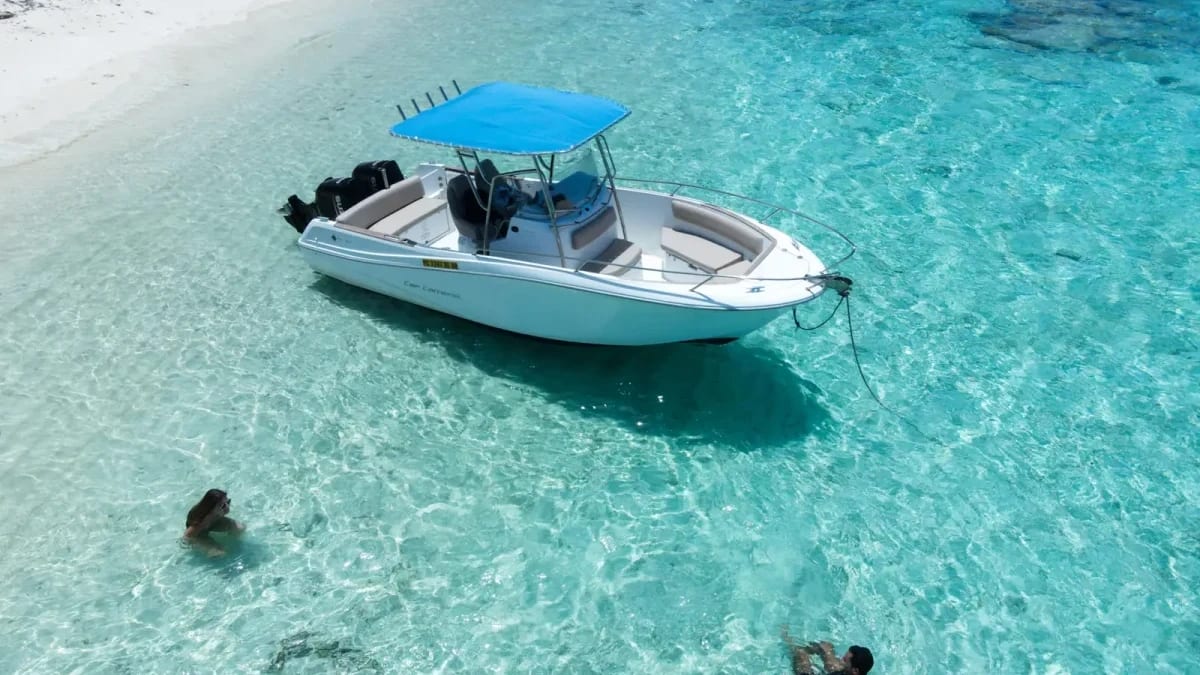 A small boat anchored beside swimmers in clear water