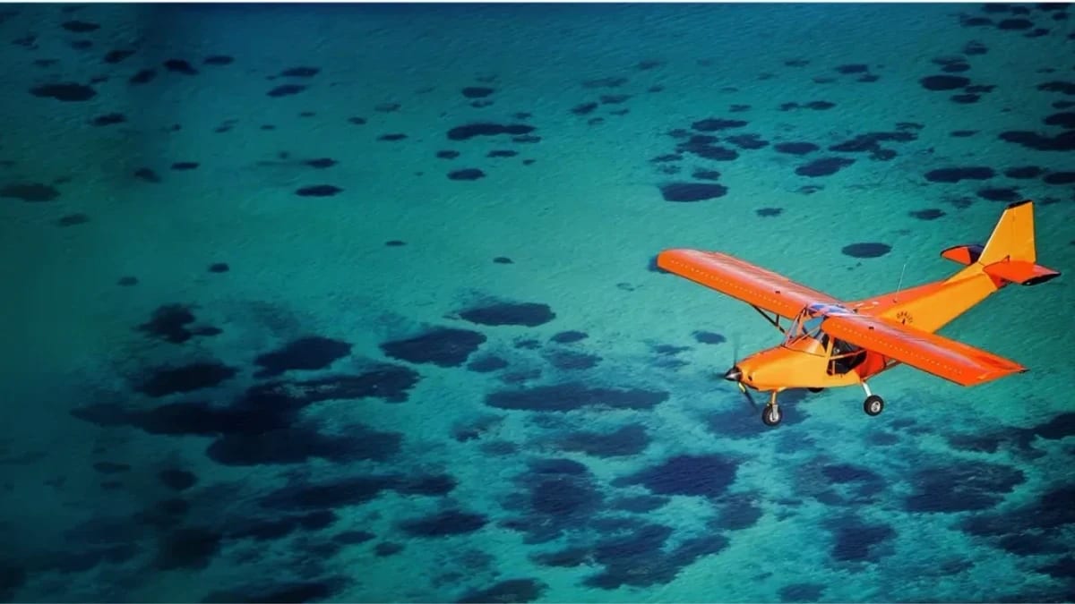 Ein orangefarbenes Ultraleichtflugzeug über einer türkisfarbenen Lagune