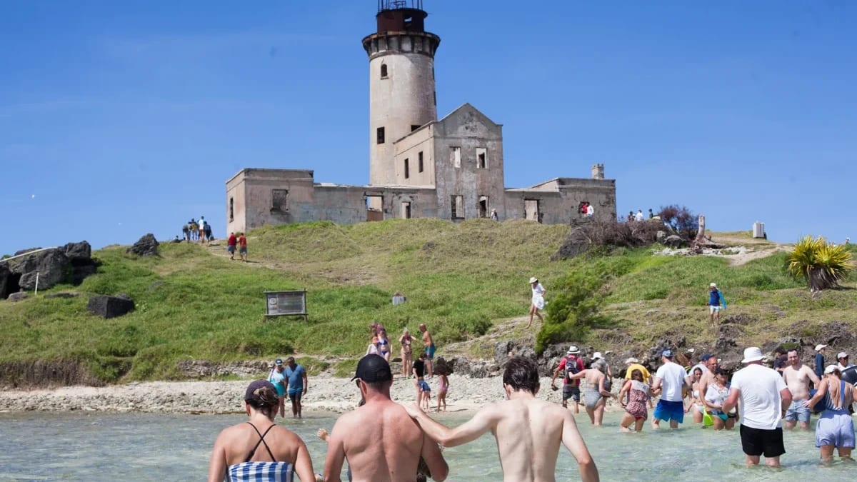 Des visiteurs rejoignent un îlot avec un phare