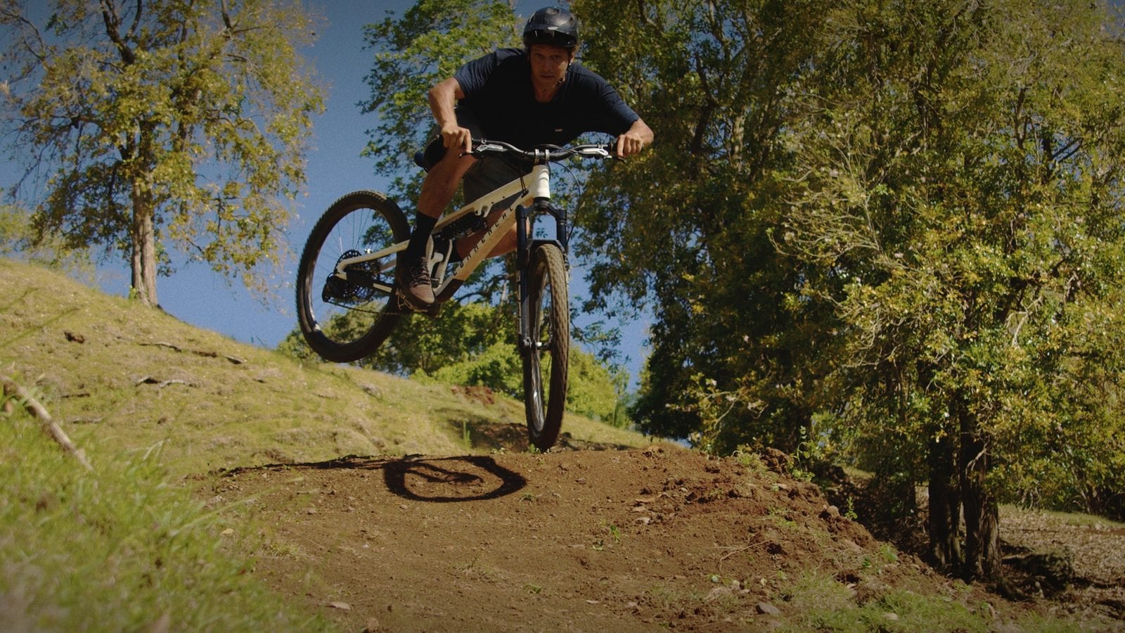 A helmeted mountain biker riding a dirt jump in Mauritius