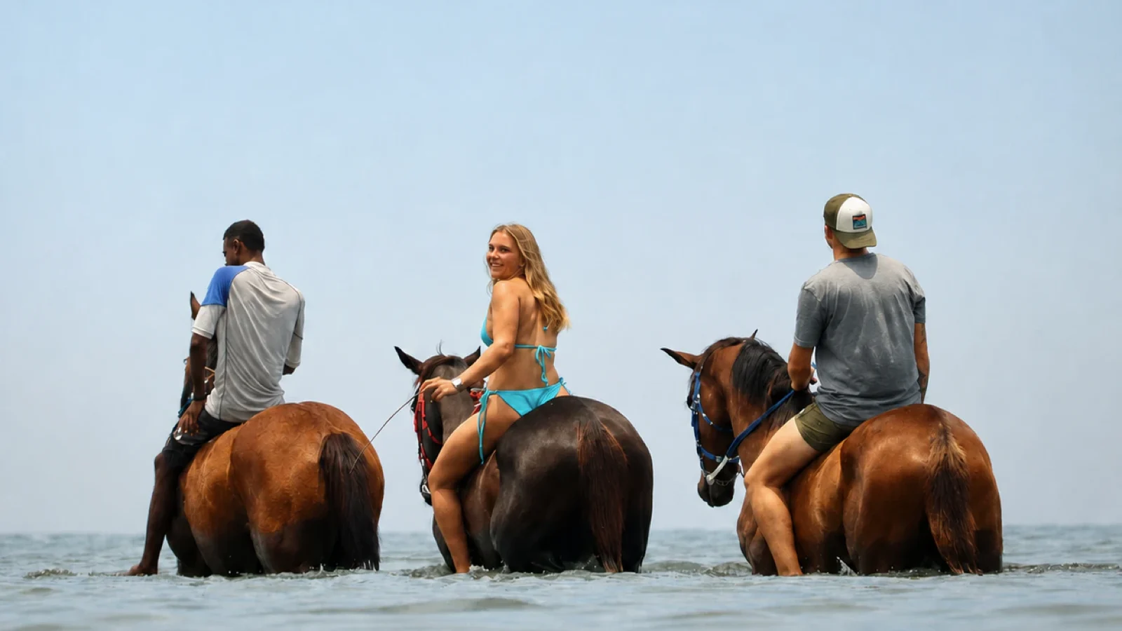 Tři jezdci na koních ve vodě laguny u Le Morne