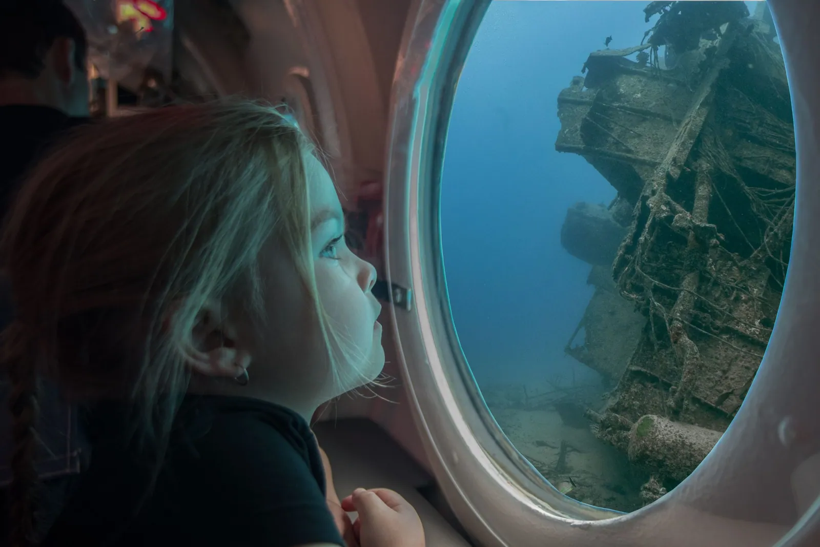 Une passagère regarde une épave par le hublot d’un sous-marin
