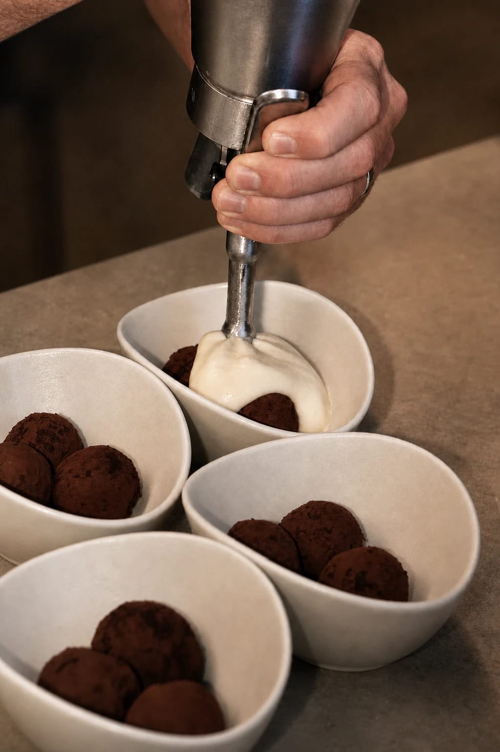Cream being added to a dessert in a white bowl
