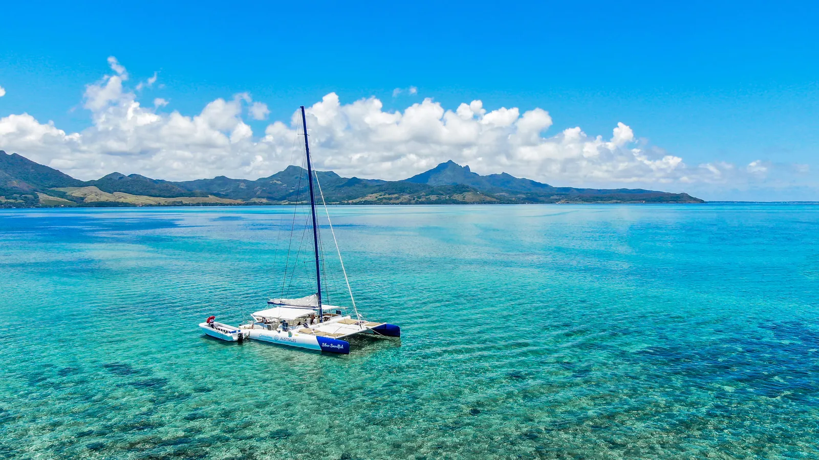 Un catamaran sur un lagon turquoise, avec des montagnes le long de la côte sud-est de l’île Maurice